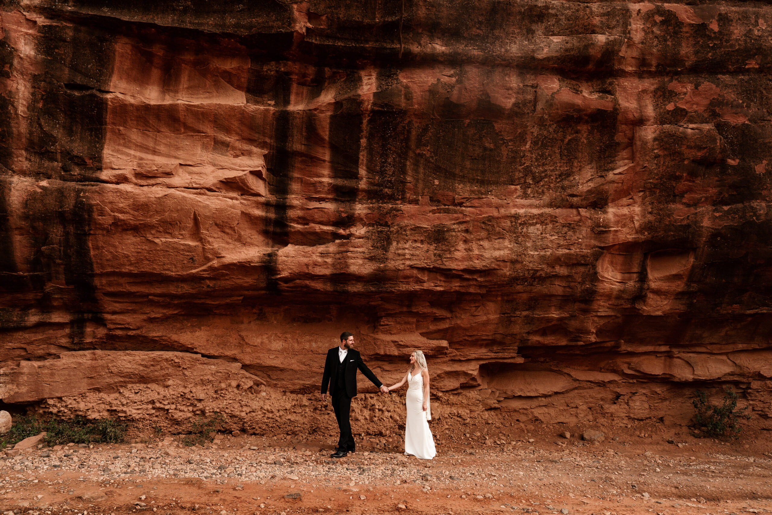 Elopement couple walking under red rock in Sedona, Arizona