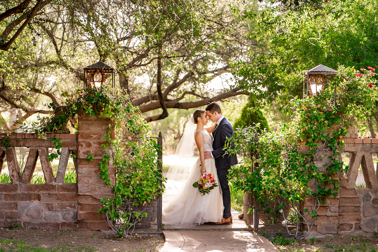 bride and groom between two brick pillars covered in ivy at Agua Linda Farm in Tucson Arizona