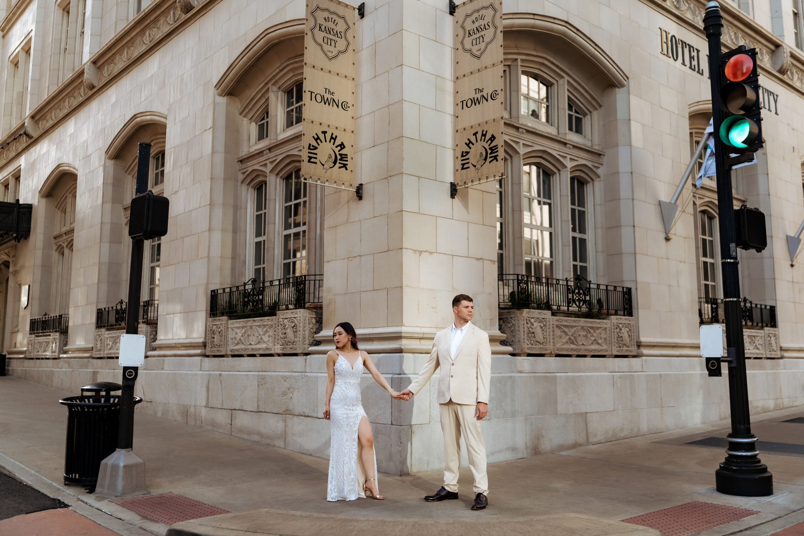 engaged couple holding hands in front of hotel kansas city during downtown engagement photo shoot