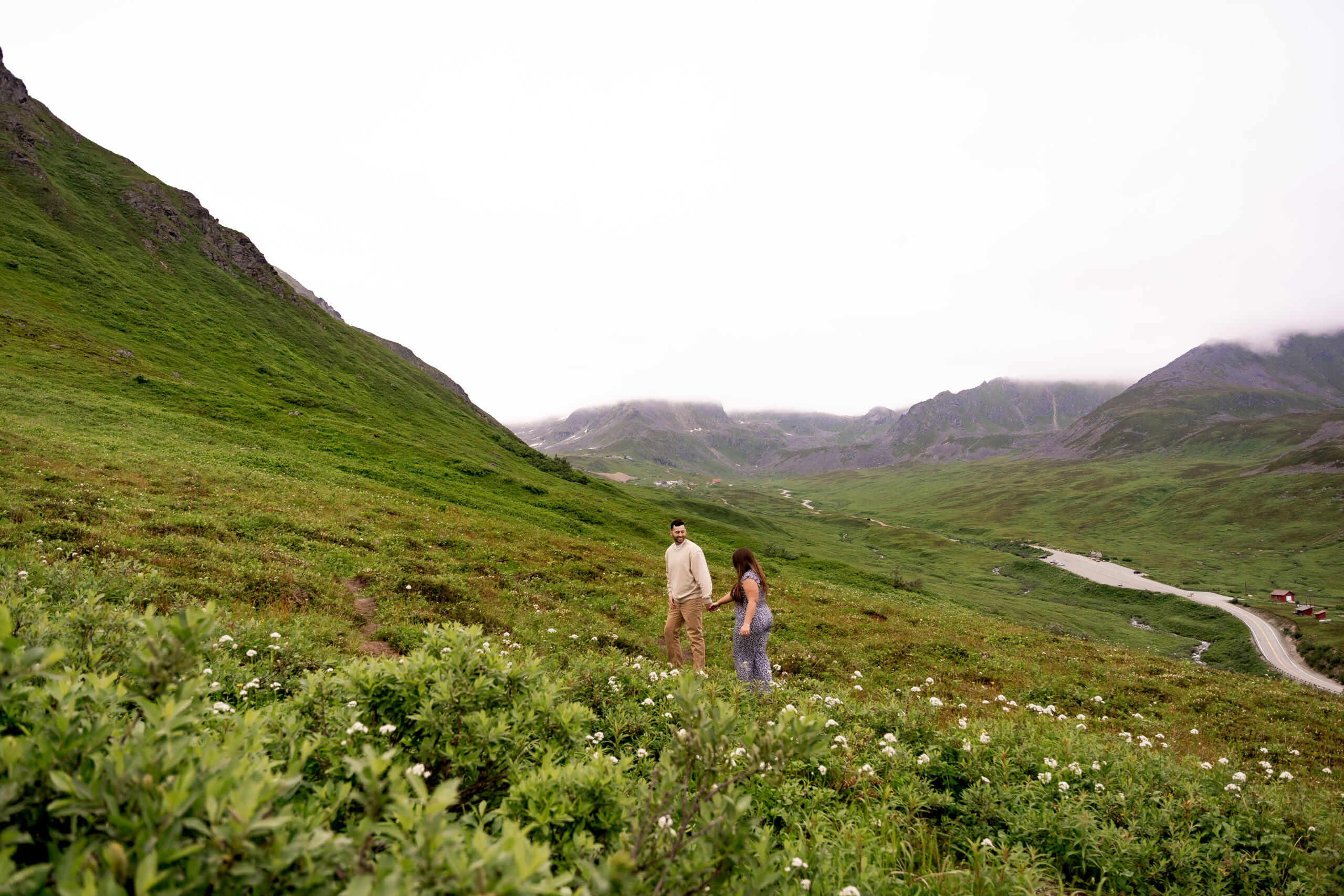 engaged couple walking in wildflowers in Hatcher Pass, Alaska