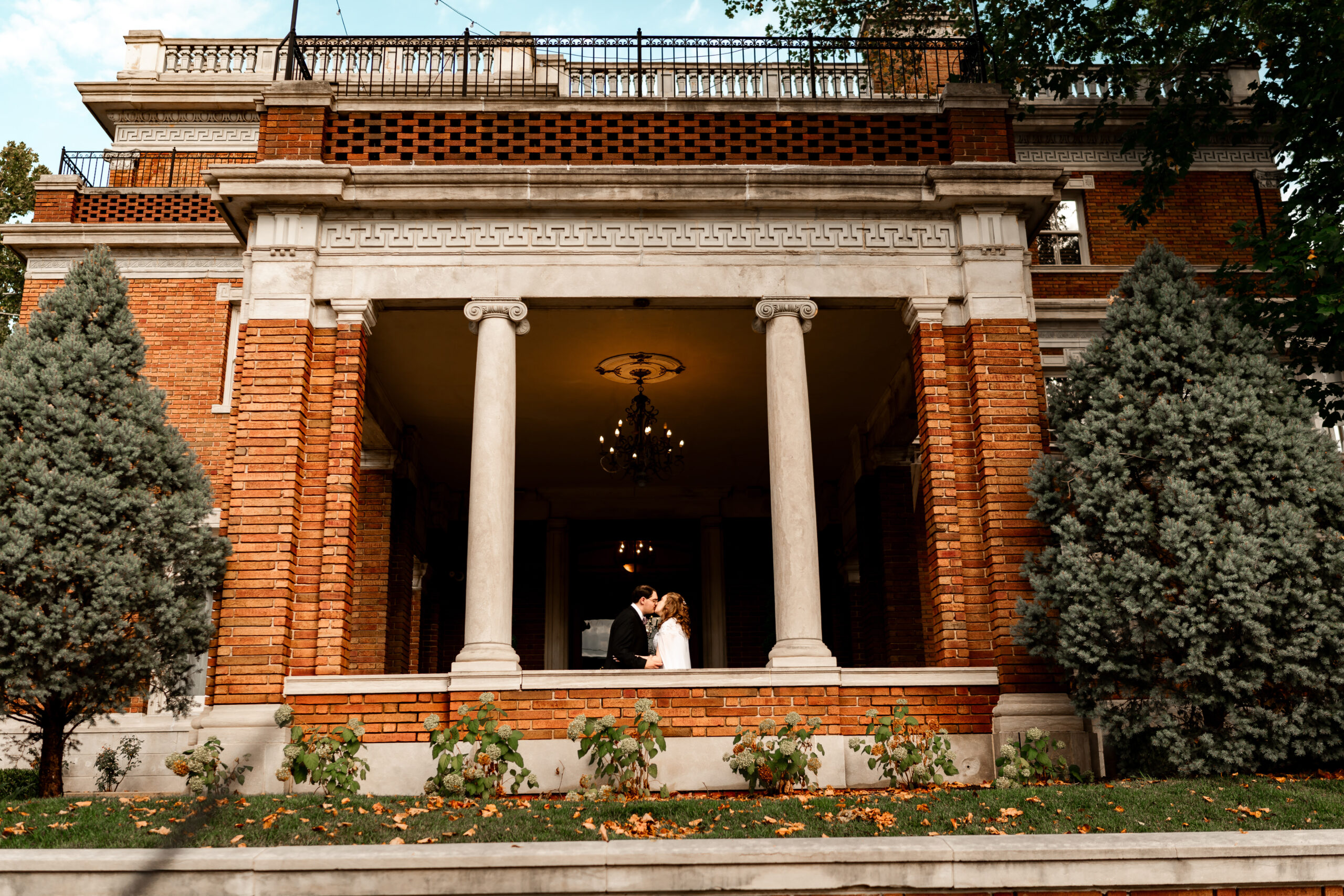 bride and groom kissing in front of loose mansion wedding venue