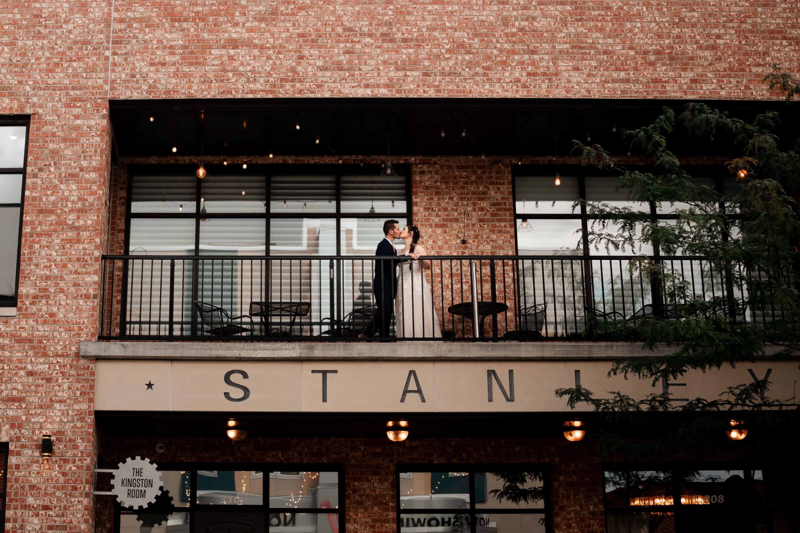 wedding bride and groom kissing on balcony of the stanley event space