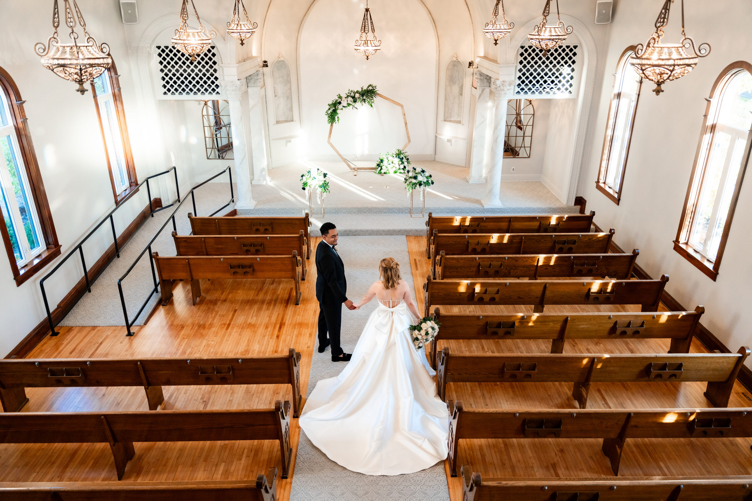 a bride and groom walk down an aisle in the Warren Place Venue chapel